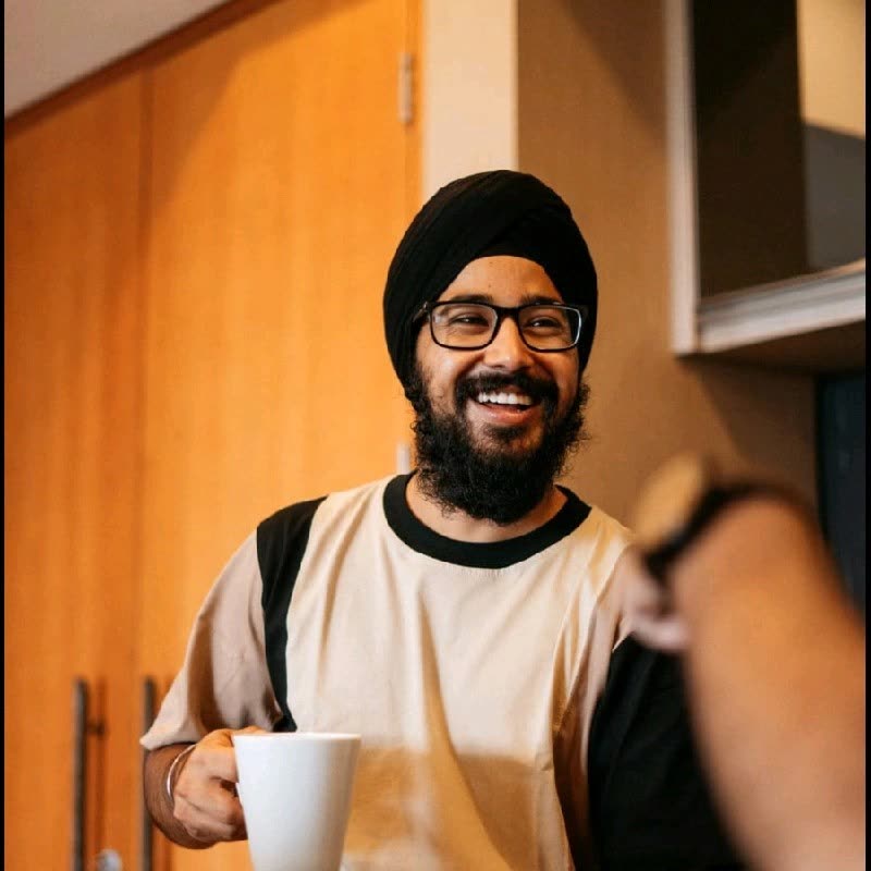 Parneet Kohli, founder of GNFK, smiling in a black turban and glasses, holding a white mug.